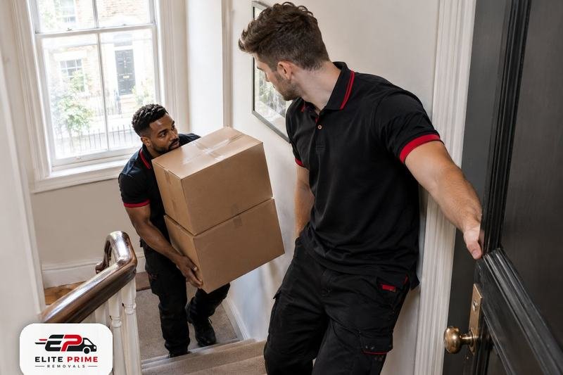 Two movers carrying boxes down a narrow staircase